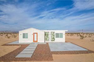 a small white house in the middle of the desert at Serene Modern Home Backdoor with great WiFi, games, movies, patio seating and bbq Easy Access to North Joshua Tree National Park in 10 minutes in Twentynine Palms
