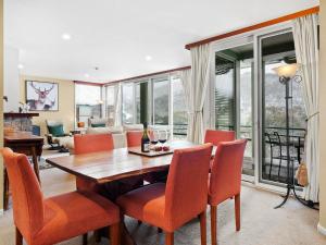 uma sala de jantar com uma mesa de madeira e cadeiras laranja em Aspect 2 em Thredbo