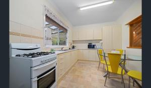 una cocina con fogones y sillas amarillas. en Holiday Heathcote en Heathcote