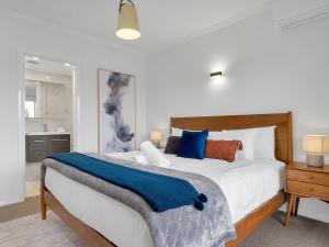 a bedroom with a large bed with a blue blanket on it at Alloura 2 in Jindabyne
