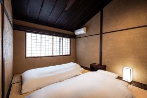 Dos camas en una habitación con ventana. en Rinn Premium Machiya Kunpu, en Kioto