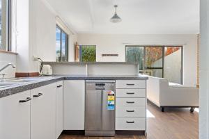 a kitchen with white cabinets and a stainless steel dishwasher at Bere Pad in Jindabyne