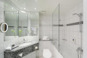 a white bathroom with a sink and a shower at Mercure Hotel Bochum City in Bochum