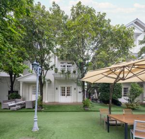 a patio with tables and an umbrella in front of a house at Hidden Mansions Saigon Resort in Ho Chi Minh City