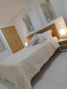 ein großes weißes Bett in einem Schlafzimmer mit zwei Fenstern in der Unterkunft Apartamento moderno frente al mar in Cartagena de Indias