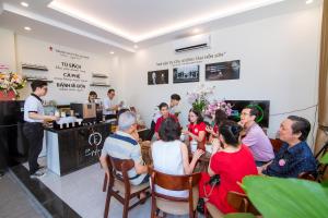 a group of people sitting around a table in a restaurant at BIG Hotel Huế in Hue