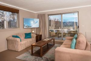 a living room with two couches and a large window at Erulisse in Jindabyne