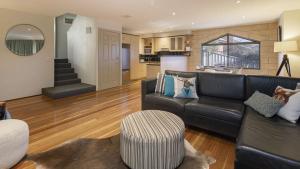a living room with a black couch and a kitchen at Glacialis 6 in Jindabyne
