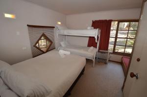 ein kleines Schlafzimmer mit 2 Betten und einem Fenster in der Unterkunft Hi Plains Garadyigan Chalet in Thredbo