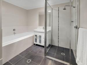 a white bathroom with a shower and a tub at Jasper 1 in Jindabyne +7 photos