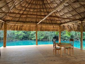 a wooden table and chairs under a thatched roof at Crystal Creek Lodge in Orange Walk