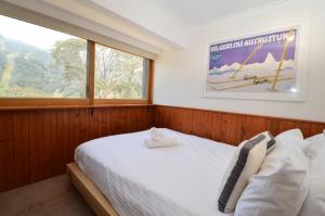 a bedroom with a large white bed with a window at Karoonda 1 in Thredbo