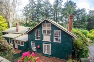 una casa verde con finestre e fiori bianchi di Ard Choille Cottages a Mount Macedon