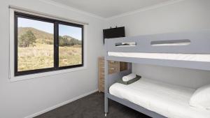 a bedroom with two bunk beds and a window at Kunama Haven in Jindabyne