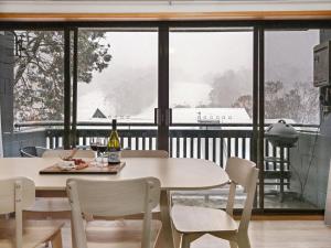a dining room with a table and chairs and a large window at Mowamba D1 in Thredbo