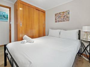 a bedroom with a large white bed with a wooden door at Mowamba D1 in Thredbo