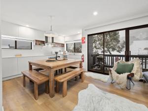 a kitchen and living room with a wooden table and bench at Mowamba A1 in Thredbo
