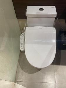 un bagno con servizi igienici bianchi e telecomando di ReLuxe マリン Condo a Maribago