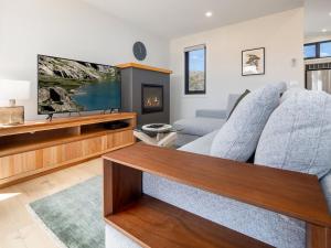 sala de estar con TV y sofá en Puggle Lodge en Jindabyne
