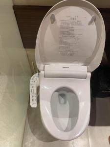 a white toilet with the lid up in a bathroom at ReLuxe マリン Condo in Maribago