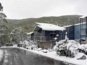 a house covered in snow next to a road at Snowbound 1 in Thredbo