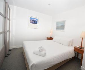 sypialnia z dużym białym łóżkiem z białą pościelą w obiekcie Squatters Run 4 w mieście Thredbo