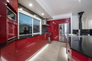 a kitchen with red cabinets and a large window at Stratton Summit 4 in Jindabyne