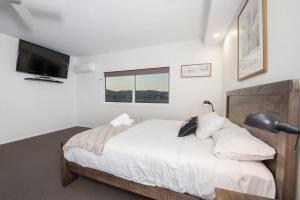 a bedroom with a bed and a flat screen tv at Stratton Summit 4 in Jindabyne