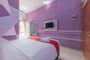 ein lila Schlafzimmer mit einem Bett und einem TV in der Unterkunft RedDoorz Syariah @ Jalan Siliwangi Tasikmalaya in Tasikmalaya