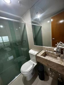 a bathroom with a toilet and a glass shower at Hotel Tropical Executive Flat 020 in Manaus