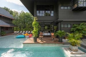 a house with a swimming pool in front of a house at Phrip Phri Luxury Pool Villas in Phetchaburi