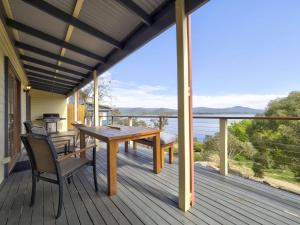 eine Holzterrasse mit einem Holztisch und Stühlen in der Unterkunft Tulong LakEscape in Jindabyne