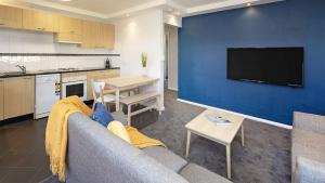 a living room with a couch and a blue wall at Yurali in Jindabyne