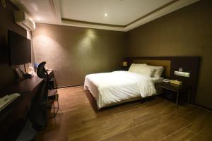 a bedroom with a white bed and a wooden floor at Lava Hotel in Seoul