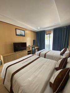 a hotel room with three beds and a flat screen tv at Khách sạn - Nhà hàng Hoàng Phúc in Tuy Phong