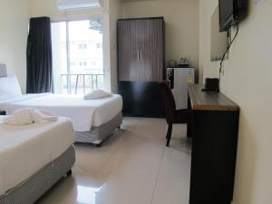 Habitación de hotel con 2 camas, escritorio y cocina en The Airy Residence, en Lat Krabang