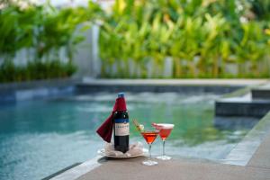 een fles wijn en twee glazen naast een zwembad bij Cozy An Boutique Hotel Hoian in Hội An