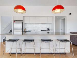 a kitchen with a counter with four bar stools at Alpine Freedom in Jindabyne