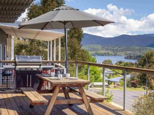 a picnic table with an umbrella on a deck with a grill at Alpine Freedom in Jindabyne