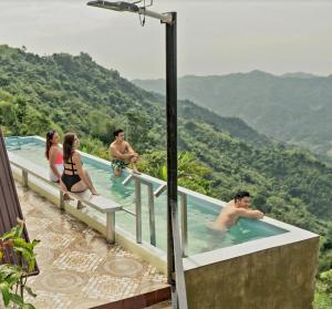 un grupo de personas en una piscina con montañas en el fondo en Guillen Plantaciones Resort Farm en Cebú