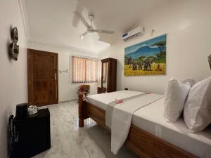 1 dormitorio con 1 cama y una pintura en la pared en Shivo Guest House, en Kiembi Samaki