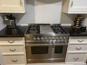a kitchen with a stainless steel stove and white cabinets at Jindaburra Cottage in Jindabyne