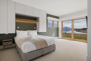 een slaapkamer met een groot bed en een groot raam bij Kosci Lakeside B in Jindabyne