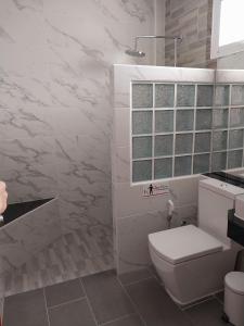 baño blanco con aseo y ventana en Tong Chang Resort, en Chumphon