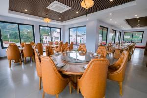 - une salle à manger avec des tables, des chaises et des fenêtres dans l'établissement Khách sạn Kumo Chan Mộc Châu, à Mộc Châu