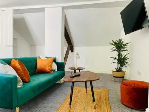 a living room with a green couch and a table at Penthouse - Contractors Professionals in Gloucester