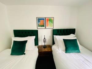 2 camas con almohadas verdes y blancas en una habitación en Penthouse - Contractors Professionals en Gloucester