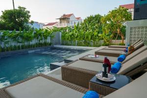 a swimming pool with chaise lounges and chairs next to a swimming pool at Cozy An Boutique Hotel Hoian in Hoi An