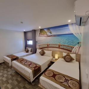a room with three beds and a painting of the ocean at Calet Hotel in Cat Ba +85 photos