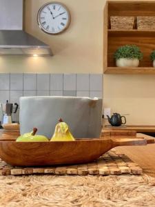 a wooden bowl of pears on a kitchen counter with a clock at A Destination To Delight! in Ballarat